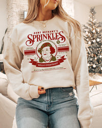 Woman wearing sand Aunt Bethany Sprinkles Christmas crewneck sweatshirt with vintage holiday graphic