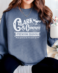Woman wearing a denim blue Clark & Company Eggnog Christmas sweatshirt while holding a festive holiday mug.
