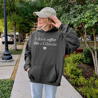 Outdoor photo of woman wearing charcoal “I Drink Coffee Like a Gilmore” hoodie – Stars Hollow inspired fall look