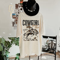 Hanging Cowgirl Social Club tee with black western hat and cowgirl boots — styled country outfit flatlay