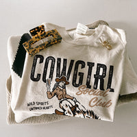 Flat lay of Cowgirl Social Club tee — ivory western graphic tee with multicolor print