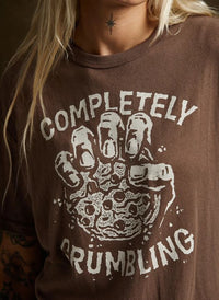 Close-up of female model wearing Pyknic's Completely Crumbling tee, featuring cookie graphic. Casual outfit with black jeans.