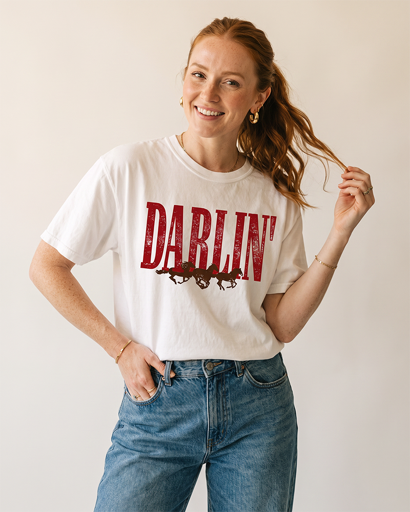 Woman wearing a white Darlin' Western horse tee with vintage distressed graphic and blue jeans.
