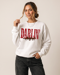 Woman modeling a white Darlin' Western horse crewneck sweatshirt with vintage distressed graphic and black jeans.