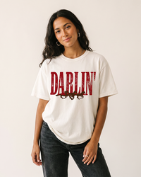 Woman wearing a white Darlin' Western horse heavyweight graphic tee with distressed lettering and black jeans.