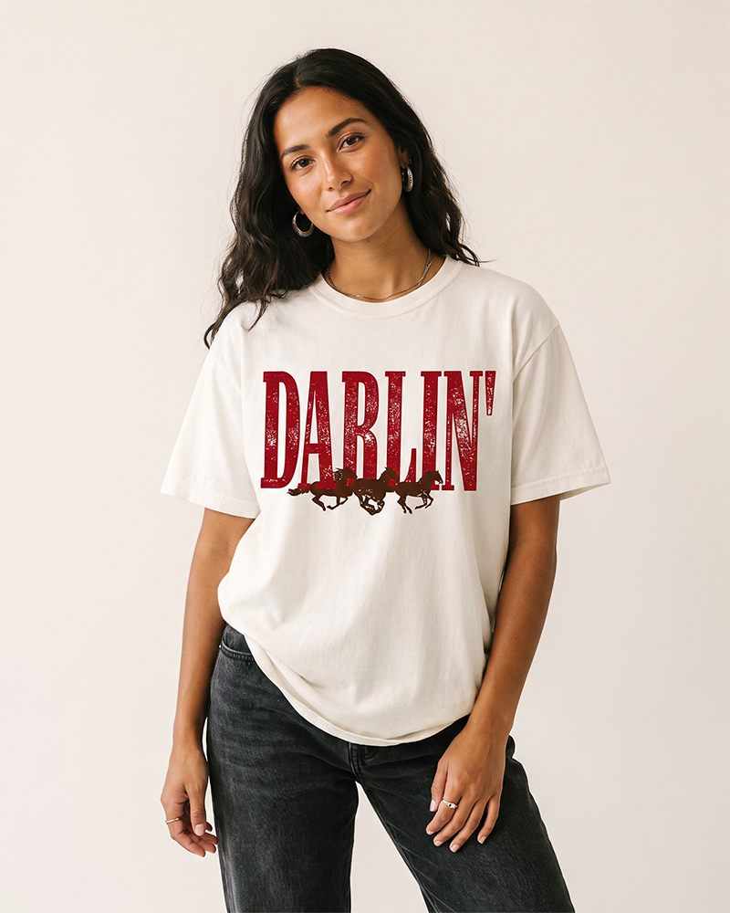 Woman wearing a white Darlin' Western horse heavyweight graphic tee with distressed lettering and black jeans.