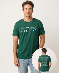 Male model wearing an evergreen green Friends-inspired Christmas lightweight tee with blue jeans, featuring the Could I BE Any More Festive front graphic and holiday quotes on the back.