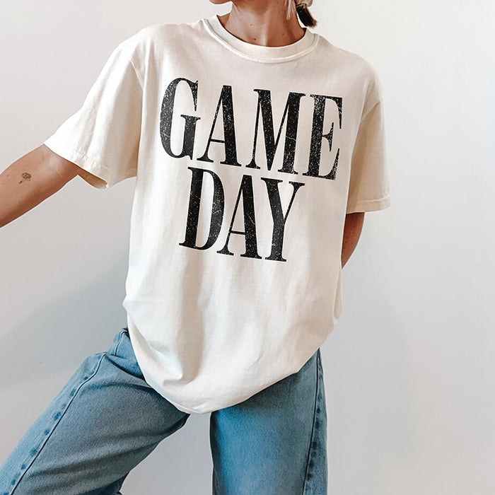 Woman wearing ivory Game Day heavyweight tee with jeans and sneakers — casual unisex sports shirt for everyday wear.