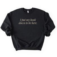 Flatlay of I Put My Book Down To Be Here Sweatshirt in black – funny bibliophile sweatshirt.