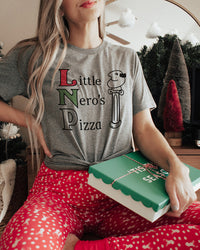 Woman wearing a Little Nero's Pizza triblend tee with red Christmas pajama pants and holding a pizza box.