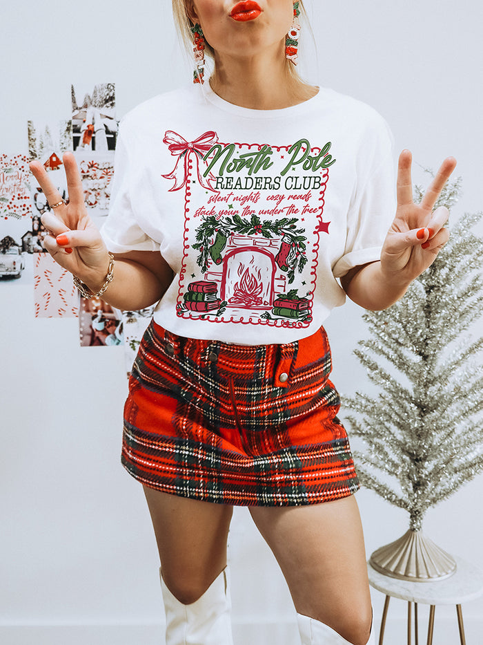 Lightweight white bookish Christmas tee with fireplace and books graphic — festive unisex reading shirt