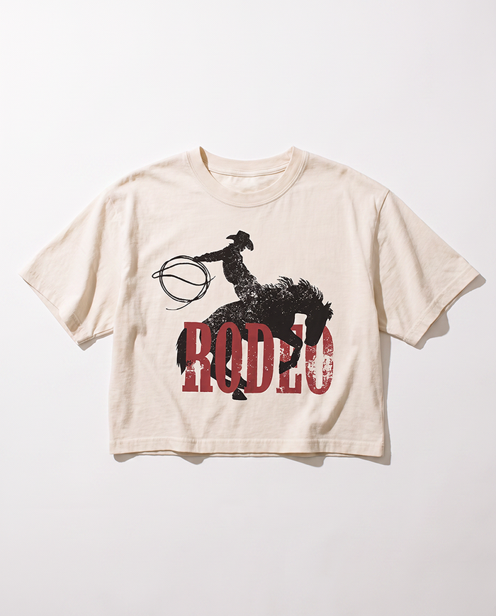 Ivory Rodeo Western boxy crop top with distressed black cowboy and bucking horse graphic over red lettering.