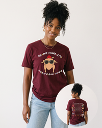 Woman with curly black hair wearing a maroon The One Where It's Thanksgiving tee with light blue denim, featuring front and back Friends-inspired graphics.
