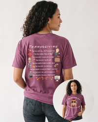Woman with curly dark hair wearing a berry purple Friends Thanksgiving heavyweight tee with vintage black jeans, showing the episode-inspired back print and turkey front design.