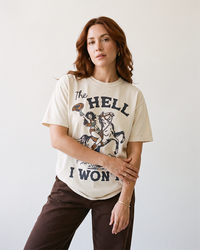 Woman wearing an ivory Western graphic tee featuring a cowgirl on horseback and The Hell I Won't lettering.