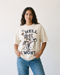 Woman wearing The Hell I Won't Western cowgirl heavyweight tee in ivory with blue jeans.