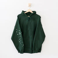 Flat lay of forest hoodie sleeve — graphic sleeve print on green camping hoodie