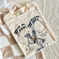 Flat lay of Wild West Cowgirl Club tee in ivory — multicolor western graphic on heavyweight cotton