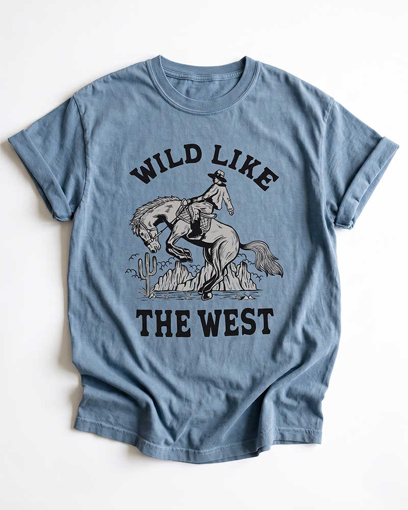 Blue Jean Wild Like The West heavyweight tee with black cowboy, bucking horse and desert Western graphic.