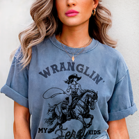 Model wearing Wranglin’ My Feral Kids tee in blue jean — funny western mom graphic t-shirt