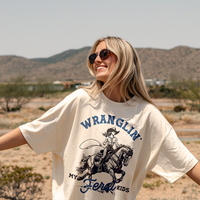 Model outdoors in ivory cowgirl mom tee — relaxed fit funny graphic tee