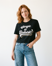 Redhead woman wearing black Allergic to Bullshit graphic crop top with high waisted blue jeans