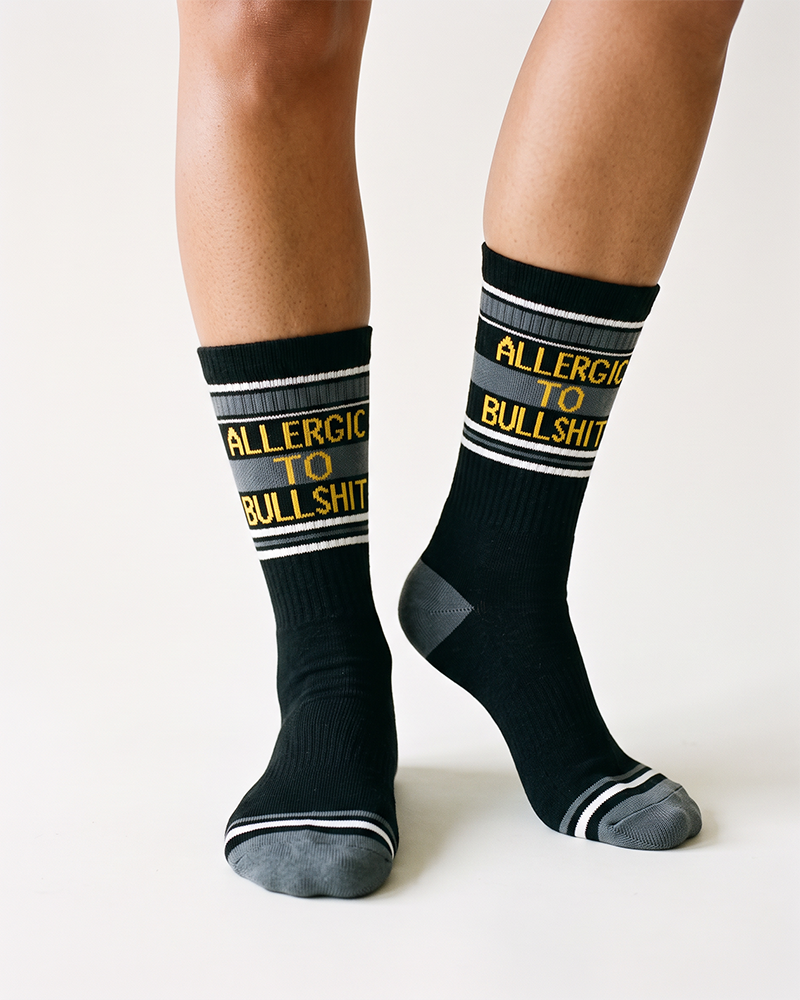 Close-up of black Allergic To Bullshit novelty crew socks with gray heels and toes