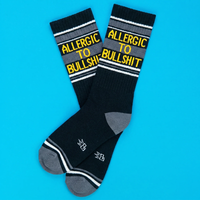 Overlapping black novelty socks featuring Allergic To Bullshit lettering and gray toe accents