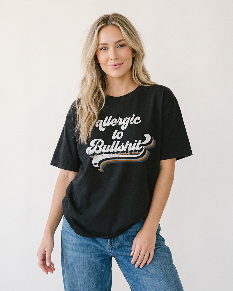 Blonde woman modeling washed black Allergic to Bullshit heavyweight graphic tee with relaxed unisex fit