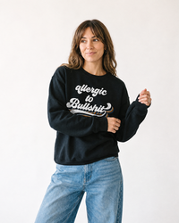 Brunette woman modeling black Allergic to Bullshit crewneck sweatshirt with vintage multicolor graphic
