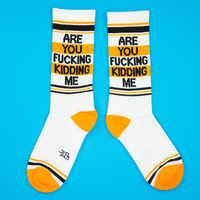 Pair of Are You Fucking Kidding Me novelty crew socks with white cotton base, orange and black stripes and bold sarcastic lettering