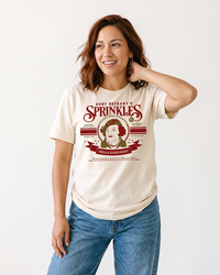Woman wearing natural Aunt Bethany Sprinkles lightweight Christmas Vacation graphic tee with jeans
