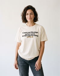 Brunette woman wearing an ivory Count Your Blessings deviled eggs Thanksgiving heavyweight tee with vintage black denim jeans.