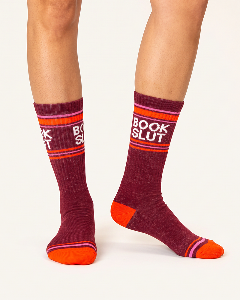 Book Slut funny book lover crew socks modeled on legs, featuring burgundy cotton and retro pink and orange stripes