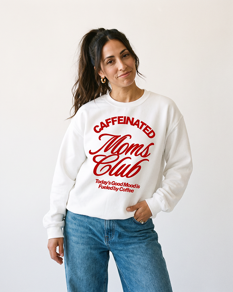 Woman wearing white Caffeinated Moms Club coffee mom crewneck sweatshirt with jeans