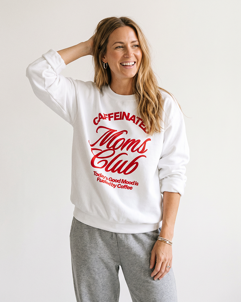 Woman wearing white Caffeinated Moms Club sweatshirt with gray lounge pants