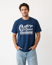 Man wearing a True Navy Clark & Company Eggnog heavyweight graphic tee with light wash jeans and hands in pockets.
