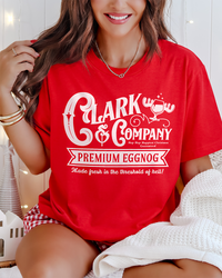 Close-up of red Clark & Company Premium Eggnog Christmas graphic shirt styled with festive plaid shorts.