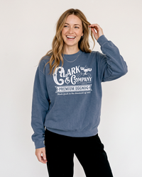 Blonde woman wearing a denim blue Clark Griswold-inspired Christmas crewneck sweatshirt with black pants.
