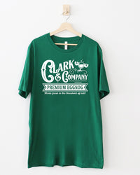 Evergreen green Clark & Company Premium Eggnog Christmas graphic tee with white vintage lettering and moose mug illustration.
