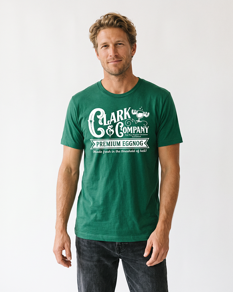 Man wearing an evergreen Clark & Company eggnog graphic t-shirt with black jeans, inspired by Christmas Vacation.
