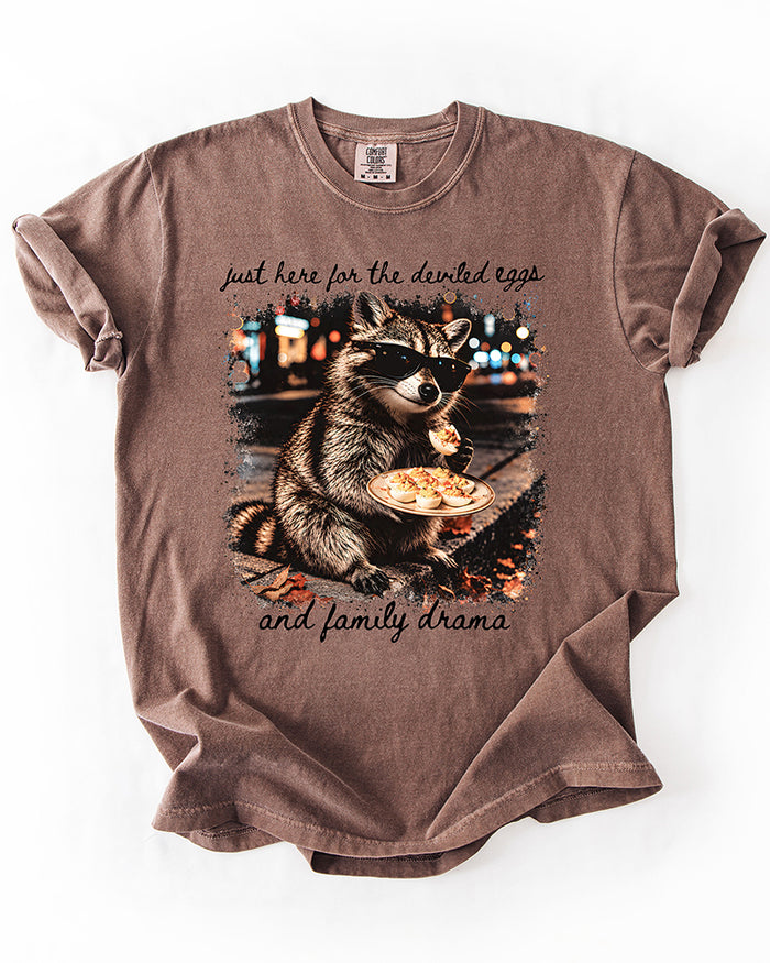 Espresso brown heavyweight graphic T-shirt featuring a raccoon holding deviled eggs with black cursive lettering.