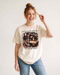 Red-haired woman wearing an Ivory heavyweight Thanksgiving raccoon graphic tee with light wash jeans.