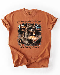 Yam orange heavyweight T-shirt featuring a raccoon wearing sunglasses, holding deviled eggs, and black family drama lettering.