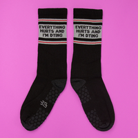 Pair of black Everything Hurts and I'm Dying grip socks with gray statement graphic