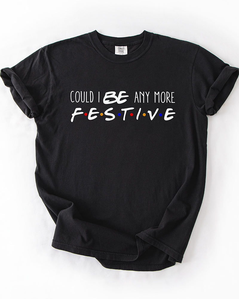 Black heavyweight Christmas graphic tee featuring Could I BE Any More Festive typography with colorful Friends-inspired dots.