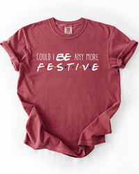 Brick red Could I Be Any More Festive heavyweight graphic tee featuring playful white lettering and multicolored dots inspired by Friends.