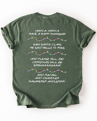 Back of hemp green Christmas heavyweight tee featuring Phoebe's Friends holiday song lyrics separated by colorful Christmas light strands.