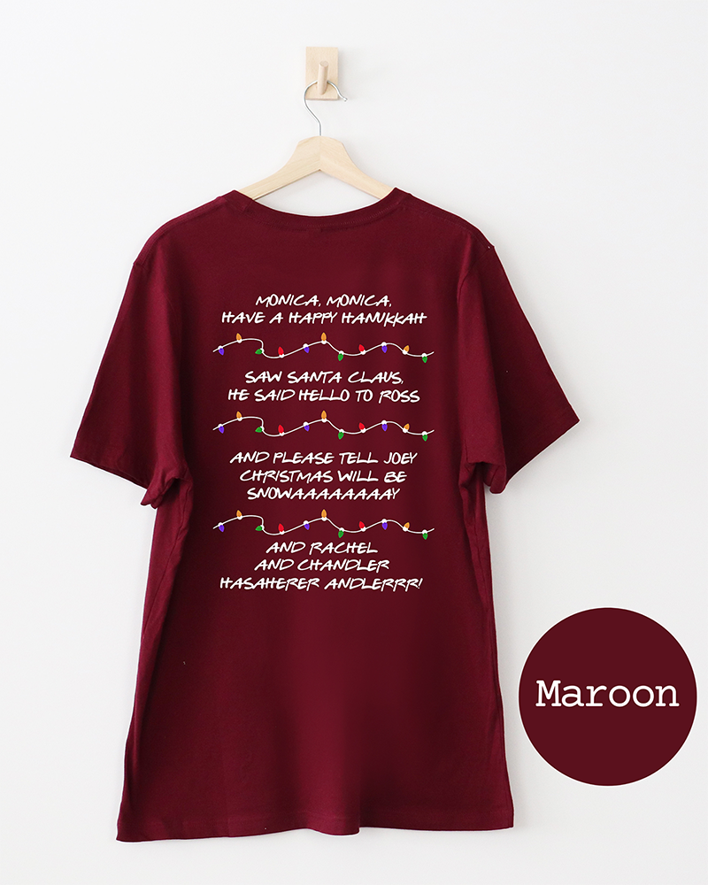 Back of maroon Friends Christmas graphic T-shirt featuring holiday quotes from the sitcom and festive multicolored Christmas lights.