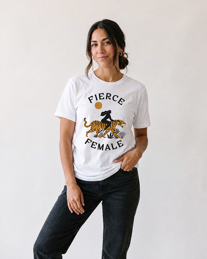 Woman wearing white Fierce Female tiger graphic t-shirt with black jeans